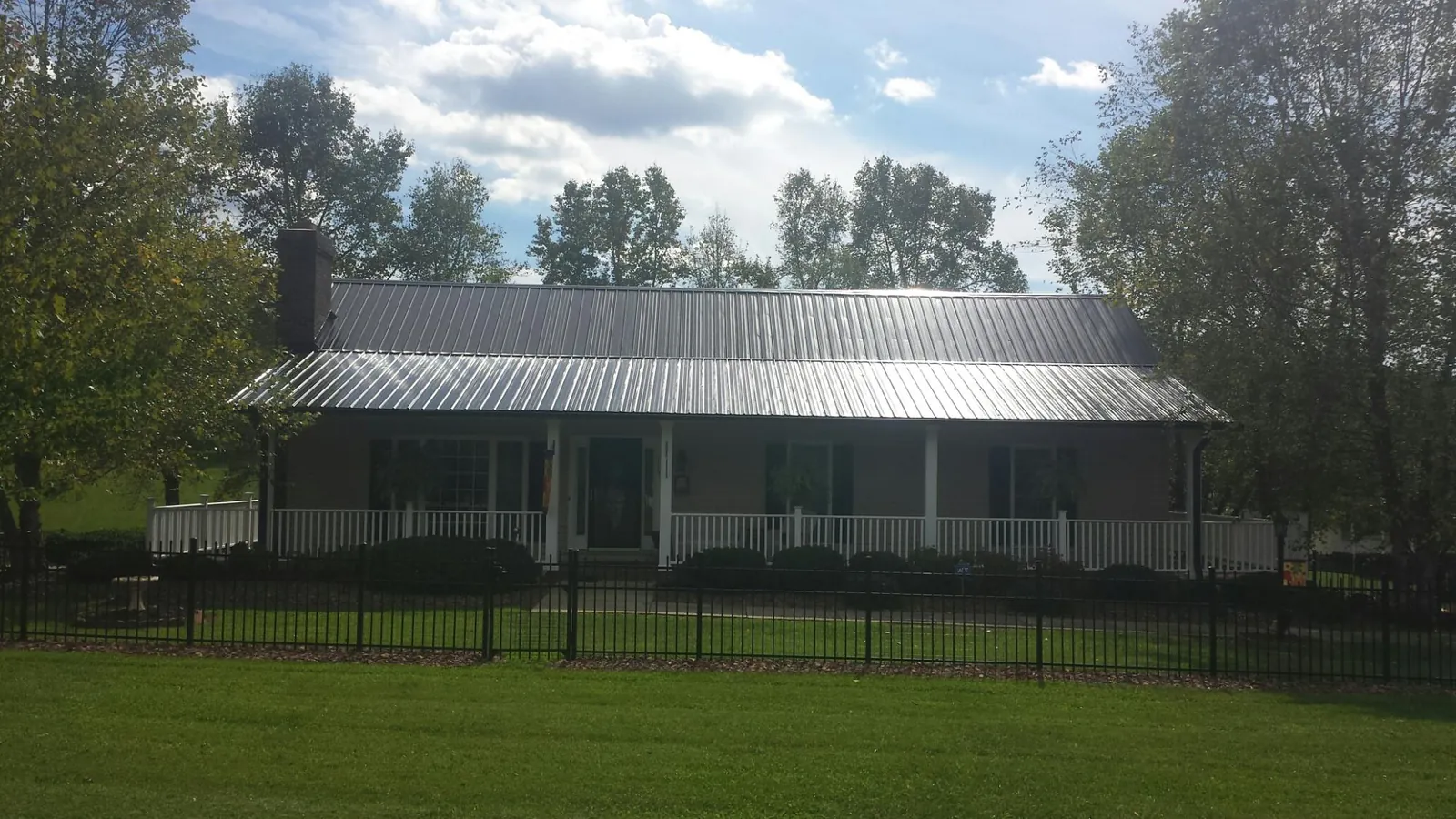 Gray metal roof on a brick ranch with a full width front porch — Gutter Guard Installation work by our crew in Charleston