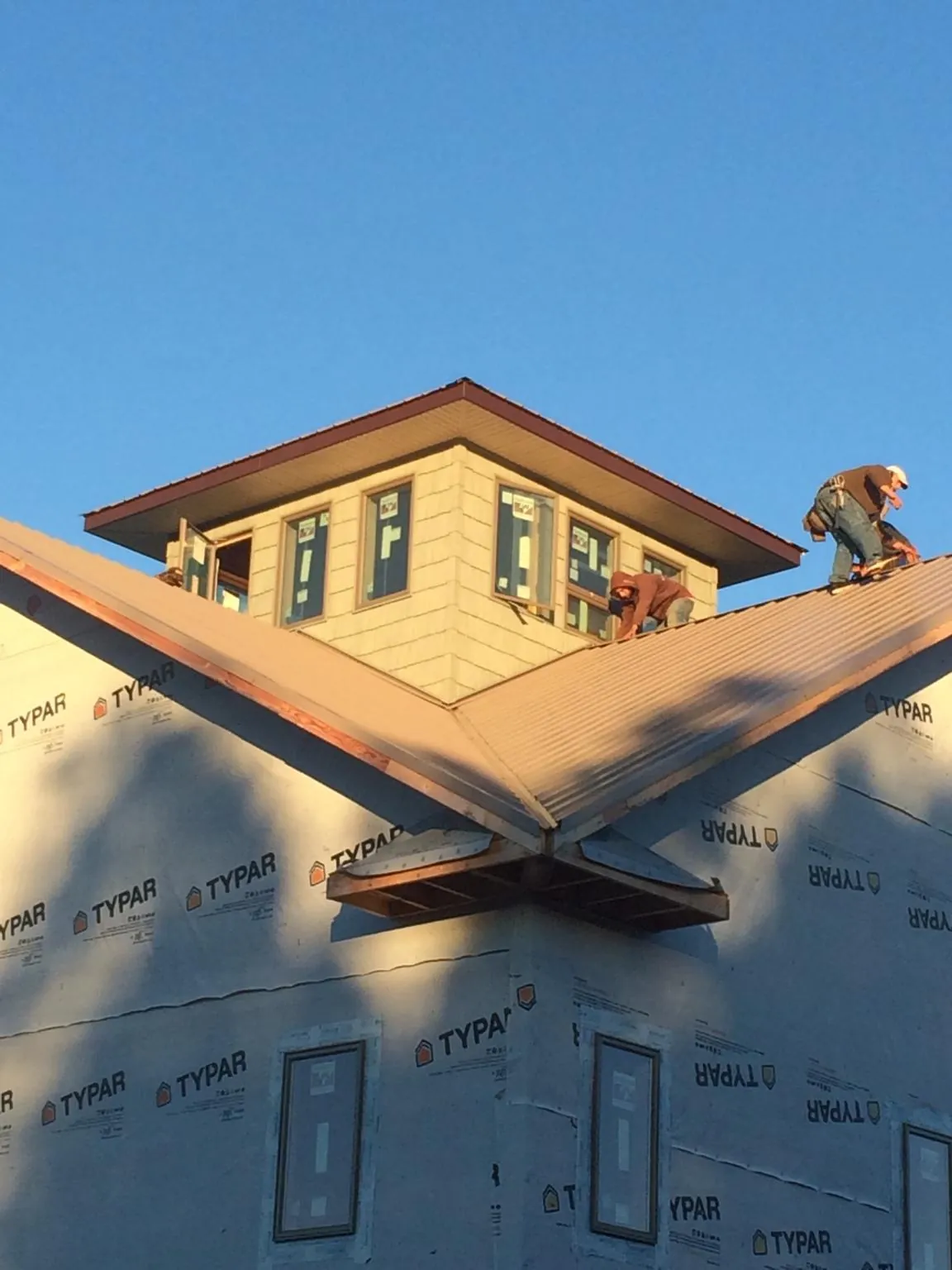 Roofers working around a rooftop cupola on a new metal roof at sunset — Roof Waterproofing in Charleston by Roofing Brothers